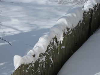 Snow on top of a fence