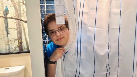 Elyse peeks out from behind a shower curtain