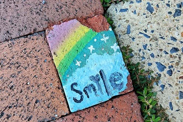 "Smile" painted on a sidewalk brick