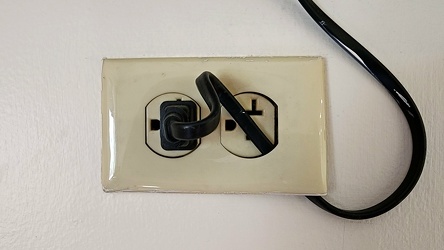 Cord secured behind wall plate